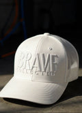White cap with 'BRAVE COLLECTIVE' text on a white background
