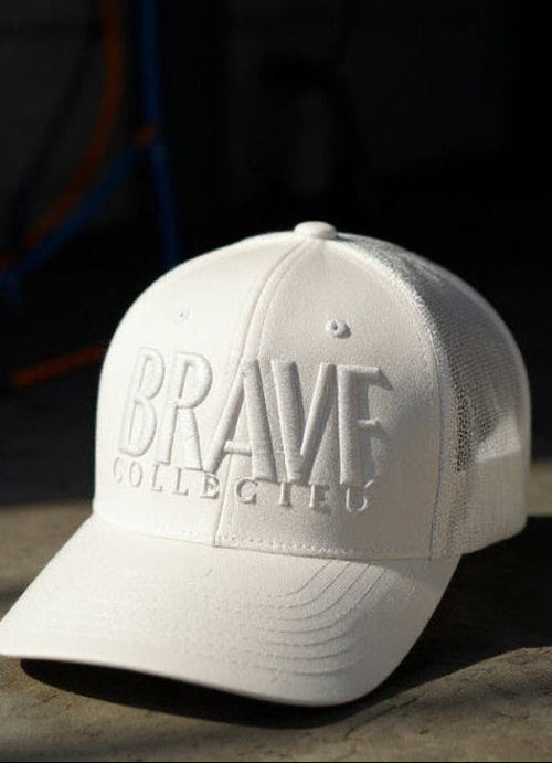 White cap with 'BRAVE COLLECTIVE' text on a white background